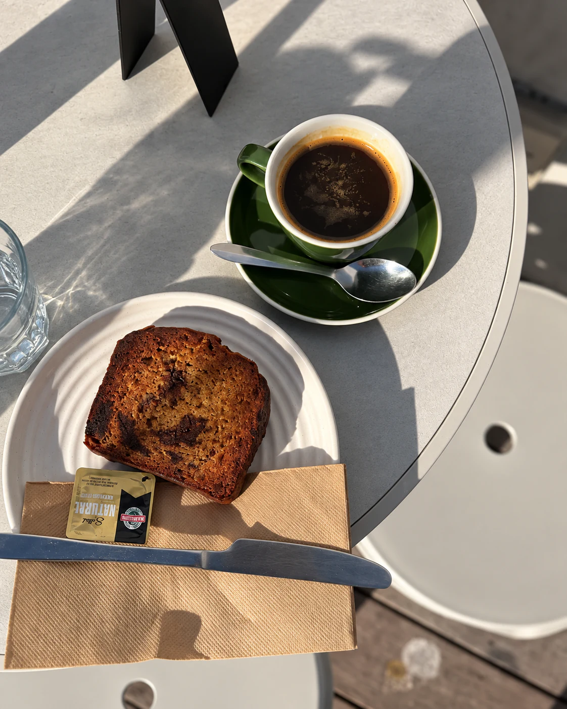 Black coffee and banana bread on an outdoor table